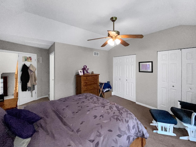 bedroom featuring lofted ceiling, multiple closets, visible vents, and carpet floors