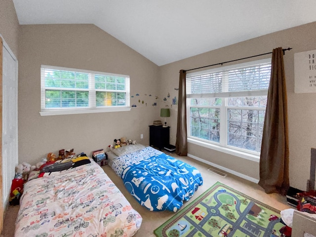 bedroom featuring lofted ceiling, multiple windows, visible vents, and carpet