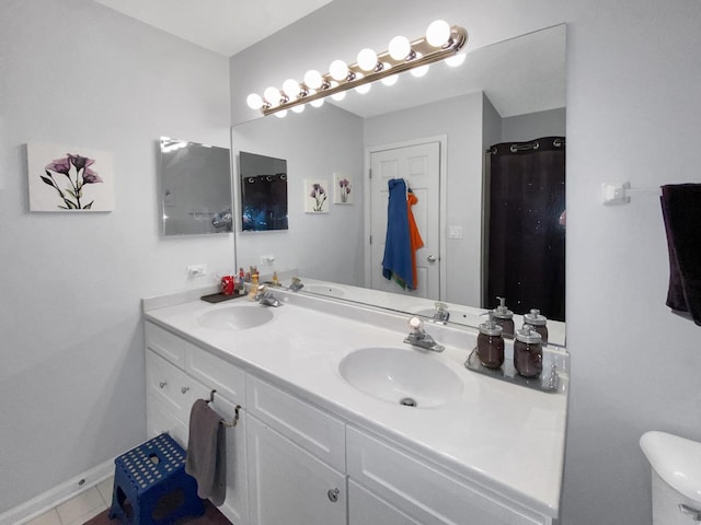 bathroom with baseboards, a sink, double vanity, and toilet