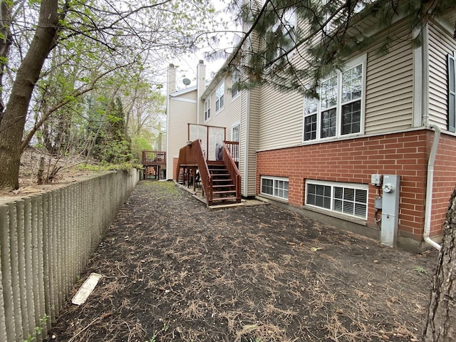 view of side of home featuring brick siding, stairway, and a deck