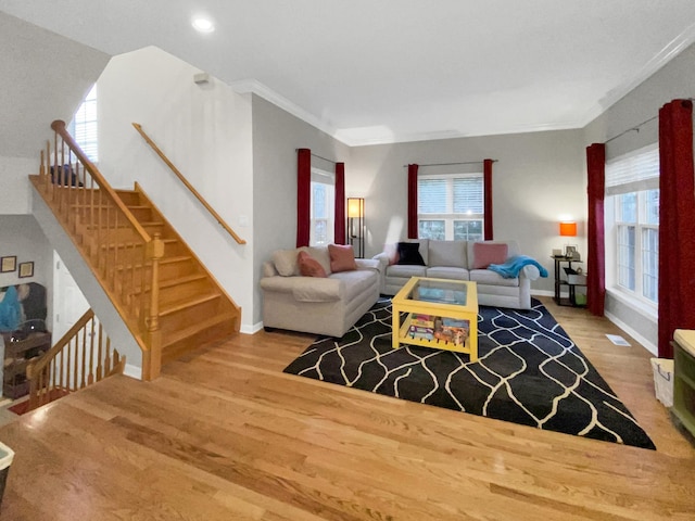 living area with wood finished floors, baseboards, and ornamental molding