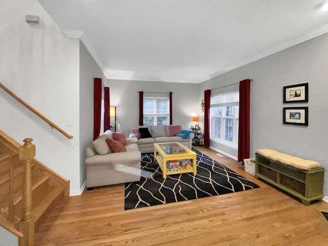 living area featuring baseboards, wood finished floors, crown molding, and stairs