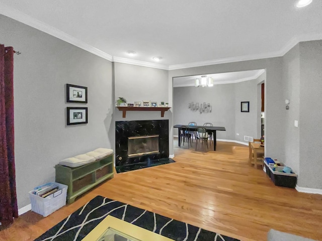 living area featuring baseboards, wood finished floors, a high end fireplace, and crown molding