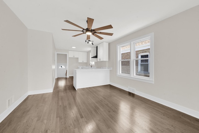 unfurnished living room featuring ceiling fan, baseboards, and dark wood-style flooring