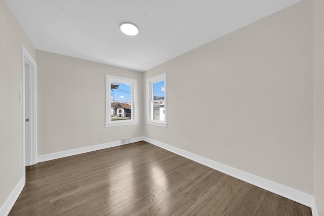 spare room featuring baseboards, visible vents, and dark wood-style flooring