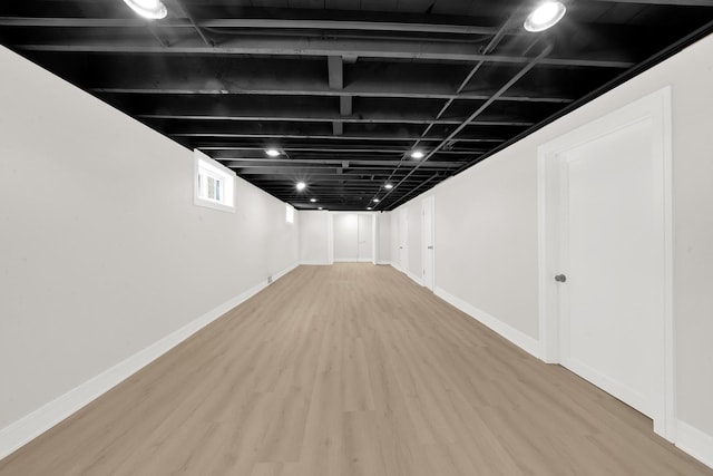 basement featuring baseboards and wood finished floors