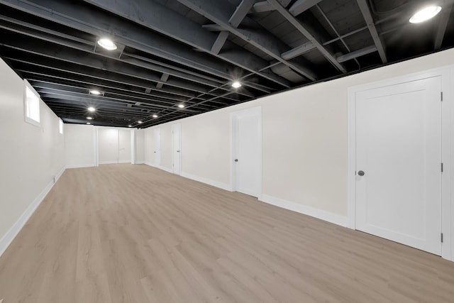 finished below grade area with light wood finished floors and baseboards