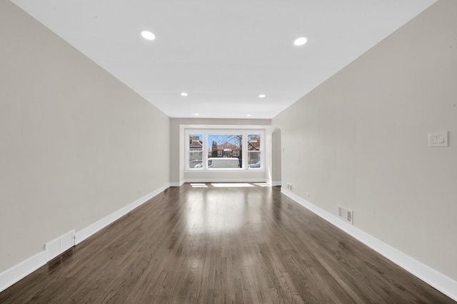 spare room featuring baseboards, visible vents, and dark wood-style floors