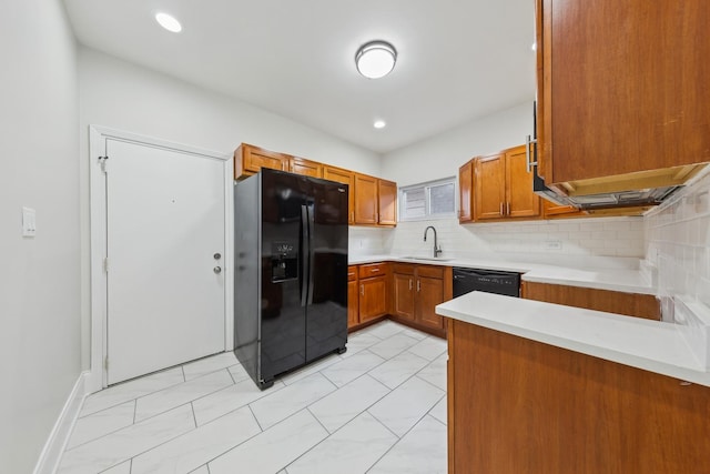 kitchen featuring a sink, tasteful backsplash, brown cabinets, light countertops, and black appliances