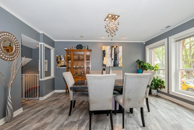 dining area featuring light wood-style floors, baseboards, and ornamental molding