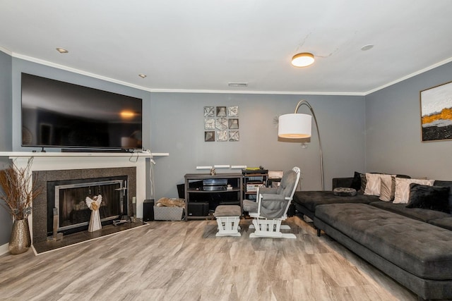 living area with crown molding, visible vents, wood finished floors, and a fireplace