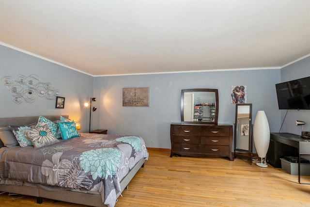 bedroom featuring crown molding, baseboards, and light wood-style flooring