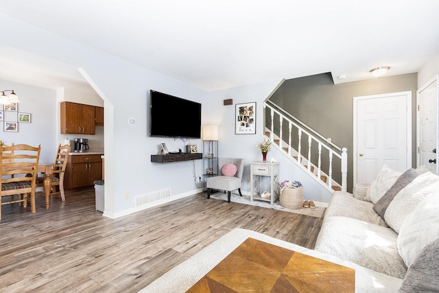 living area with stairway, visible vents, light wood finished floors, and baseboards