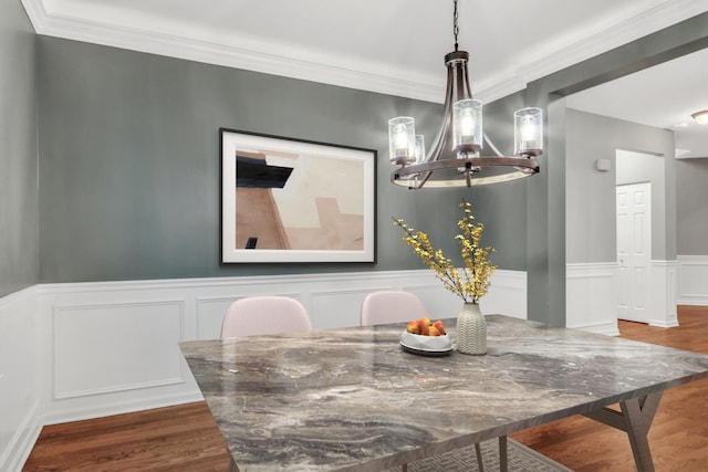 dining space with a decorative wall, a notable chandelier, wood finished floors, wainscoting, and ornamental molding