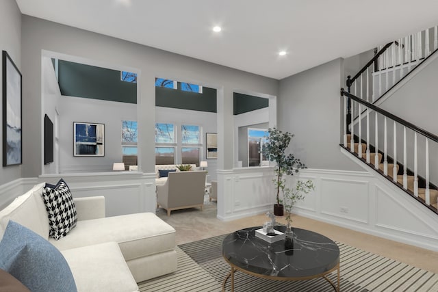living area featuring light colored carpet, a decorative wall, recessed lighting, and stairway