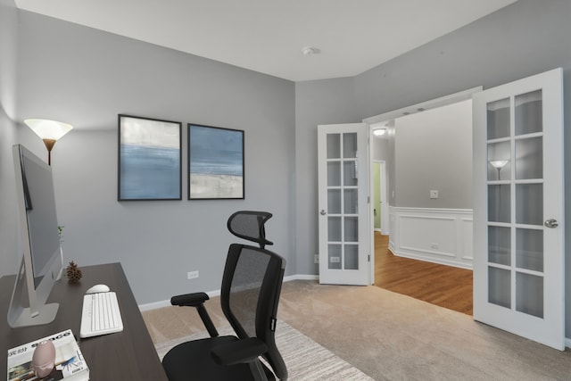 unfurnished office with french doors, carpet, and a wainscoted wall