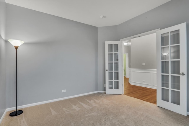 spare room featuring wainscoting, carpet flooring, and french doors