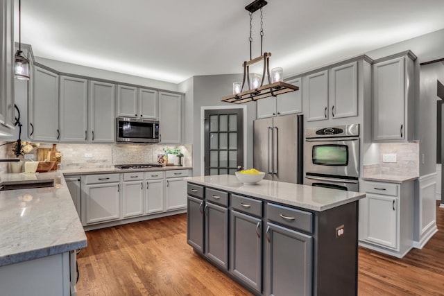 kitchen featuring tasteful backsplash, light stone countertops, appliances with stainless steel finishes, and gray cabinetry