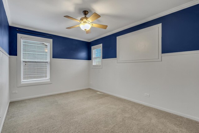 spare room with crown molding, carpet, a ceiling fan, and baseboards
