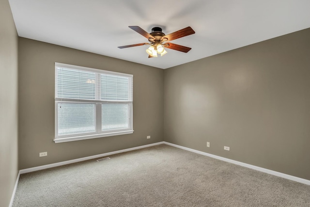 carpeted spare room with visible vents, a ceiling fan, and baseboards