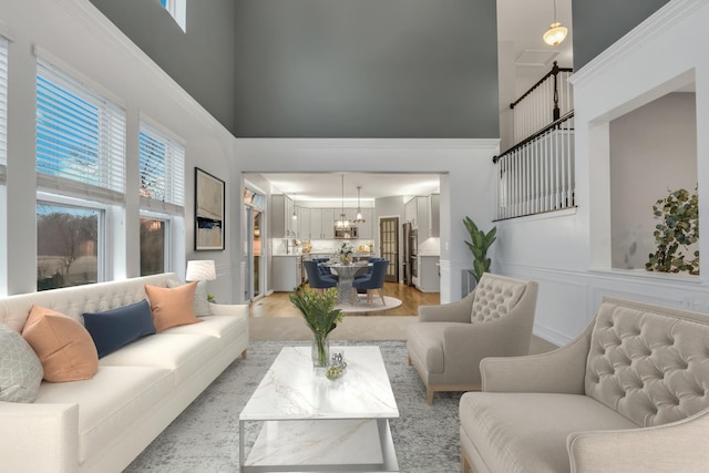 living area featuring plenty of natural light, a towering ceiling, an inviting chandelier, and light wood-style floors