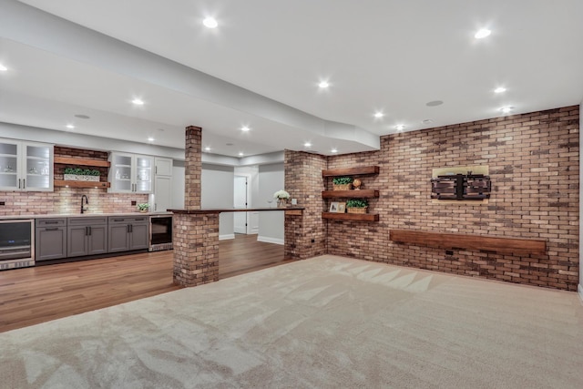bar with decorative columns, indoor wet bar, wine cooler, and light wood-style flooring