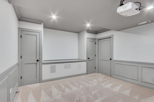 unfurnished room featuring recessed lighting, visible vents, carpet floors, a decorative wall, and wainscoting