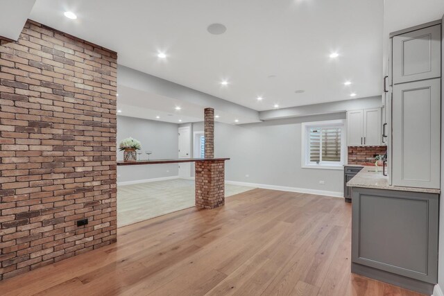 interior space with light wood-type flooring, baseboards, recessed lighting, light stone counters, and gray cabinets