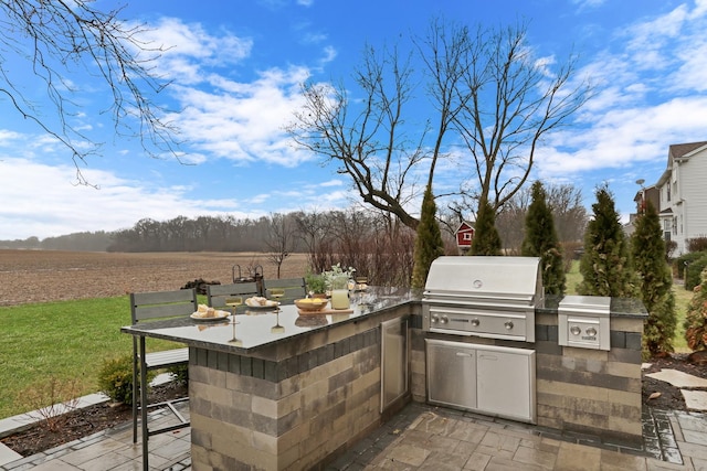 view of patio featuring grilling area, a rural view, outdoor dry bar, and exterior kitchen