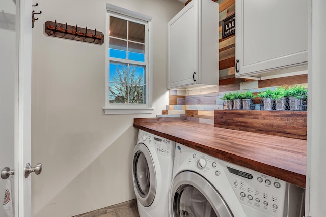 washroom featuring baseboards, cabinet space, and independent washer and dryer