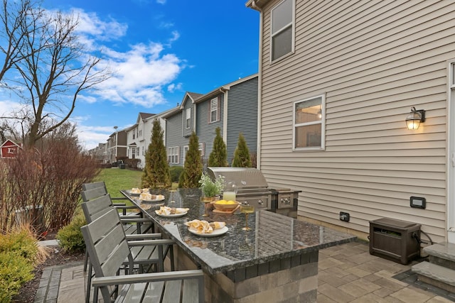view of patio with grilling area, a residential view, an outdoor kitchen, and outdoor dining space