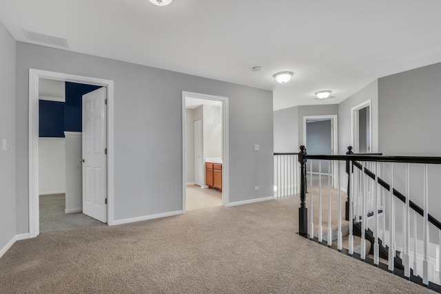 interior space with visible vents, baseboards, and light colored carpet