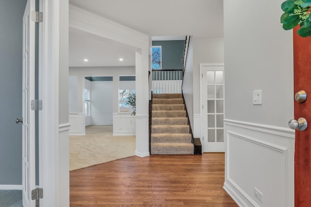 entrance foyer featuring wood finished floors, stairs, and a wainscoted wall