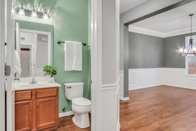 bathroom with wood finished floors, vanity, an inviting chandelier, toilet, and visible vents