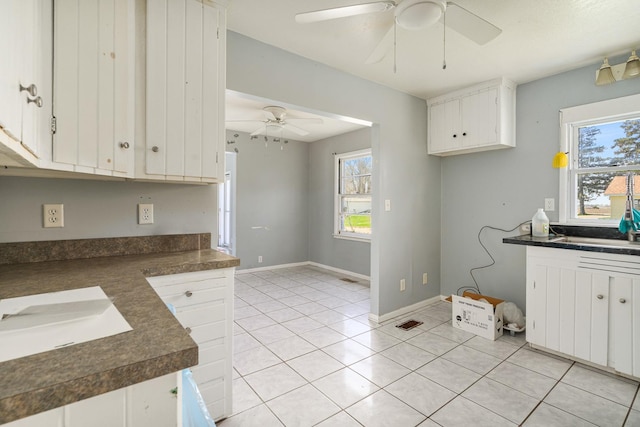kitchen featuring white cabinets, dark countertops, a ceiling fan, and a healthy amount of sunlight