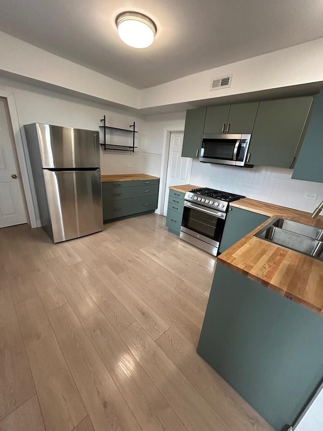 3246 S Normal Ave, Chicago, IL 60616 - kitchen featuring wood counters, stainless steel appliances, light wood-type flooring, backsplash, and green cabinetry