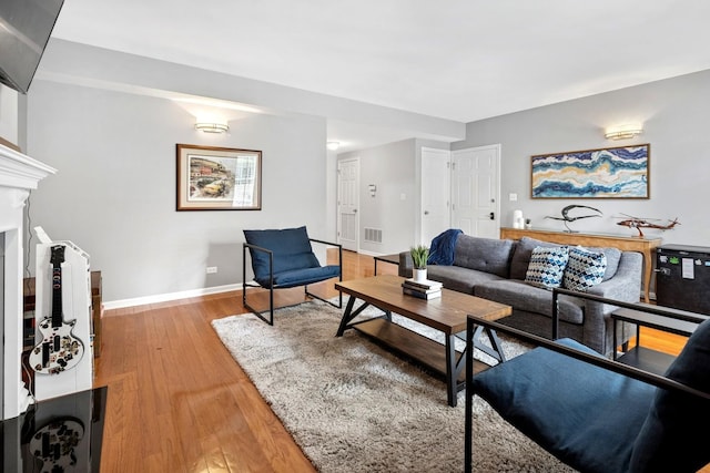 living room featuring light wood-type flooring, baseboards, and a fireplace