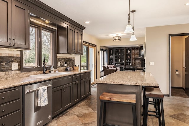 kitchen featuring a breakfast bar, tasteful backsplash, stainless steel dishwasher, and a sink