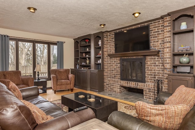 living area with built in shelves, wood finished floors, a brick fireplace, and a textured ceiling