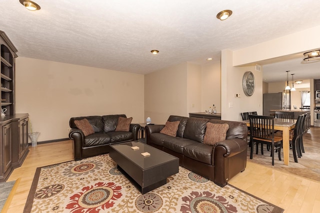 living room featuring recessed lighting, a textured ceiling, and light wood-style floors