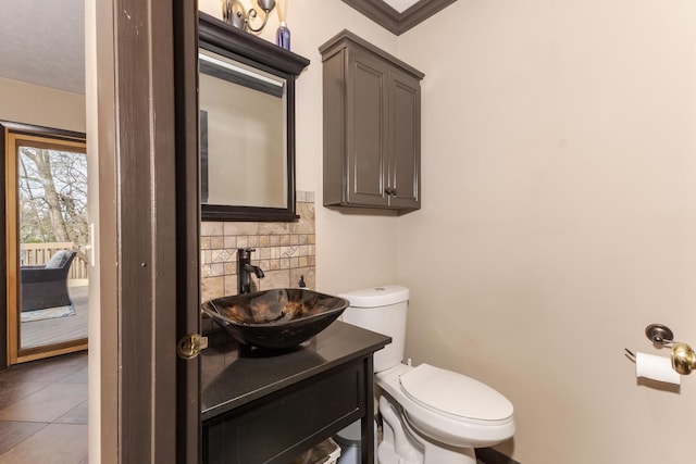 half bathroom with tile patterned floors, vanity, tasteful backsplash, and toilet