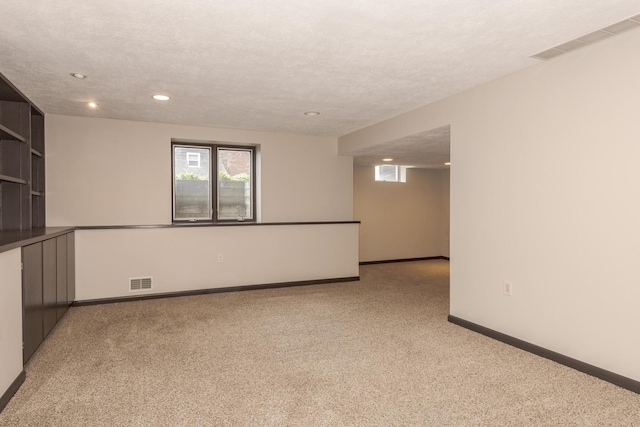 carpeted empty room featuring recessed lighting, a textured ceiling, visible vents, and baseboards