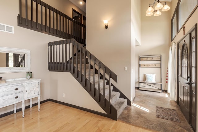interior space with visible vents, baseboards, an inviting chandelier, wood finished floors, and a high ceiling