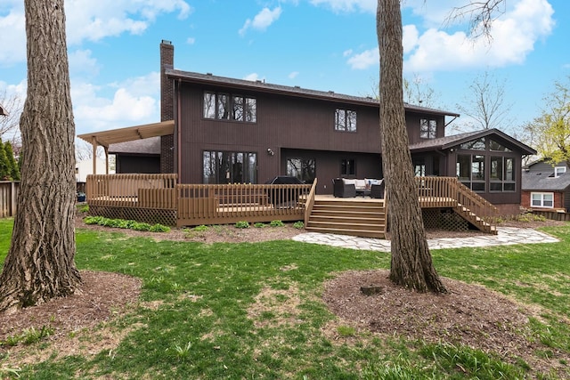 back of house featuring a chimney, a wooden deck, a sunroom, and a yard