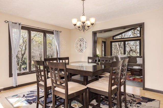 dining space with baseboards, a notable chandelier, and light wood-type flooring