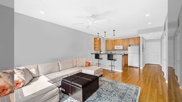 living area with ceiling fan, light wood finished floors, recessed lighting, and baseboards