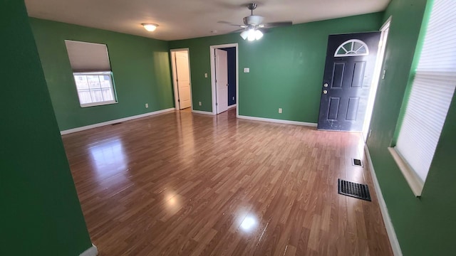 spare room with baseboards, wood finished floors, visible vents, and ceiling fan
