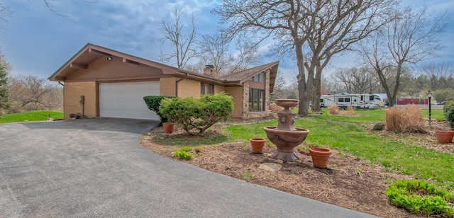 3515 Partridge Ln, Belvidere, IL 61008 - view of property exterior featuring a chimney, a lawn, driveway, an attached garage, and brick siding