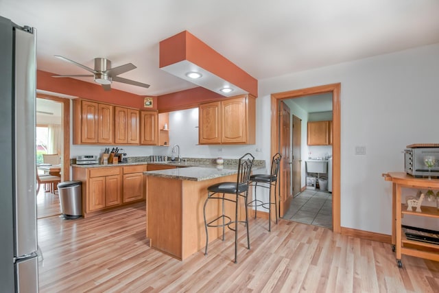 3515 Partridge Ln, Belvidere, IL 61008 - kitchen with a ceiling fan, light wood-style floors, a kitchen bar, a peninsula, and freestanding refrigerator