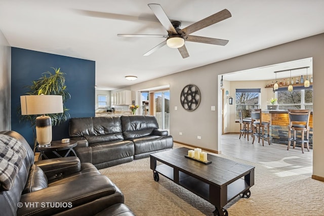 carpeted living area featuring a ceiling fan and baseboards